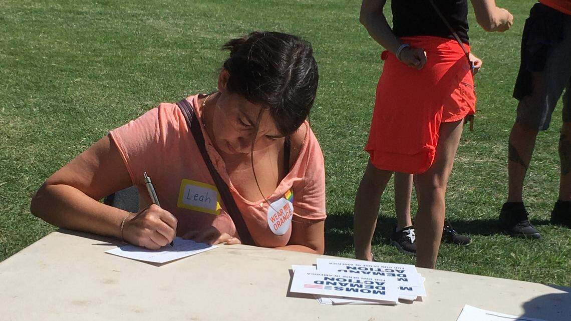 Leah Beeson, a Wake County public school teacher, writes one of two postcards to North Carolina’s U.S. senators at a gun violence prevention event Saturday, asking them to support gun safety legislation. A mother of three, Beeson brought a sign that said “Protect Lives Not Guns.”