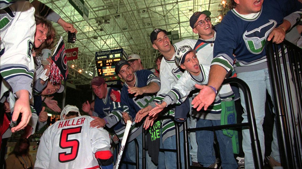 Fans in Hartford Whalers regalia cheer on Kevin Haller (5) and other members of the Carolina Hurricanes as they head for the ice before the team’s first home regular season game, against the Pittsburgh Penguins at the Greensboro Coliseum in Greensboro, N.C., on Friday, Oct. 3, 1997. The fans traveled from Hartford, Conn., to see the game.