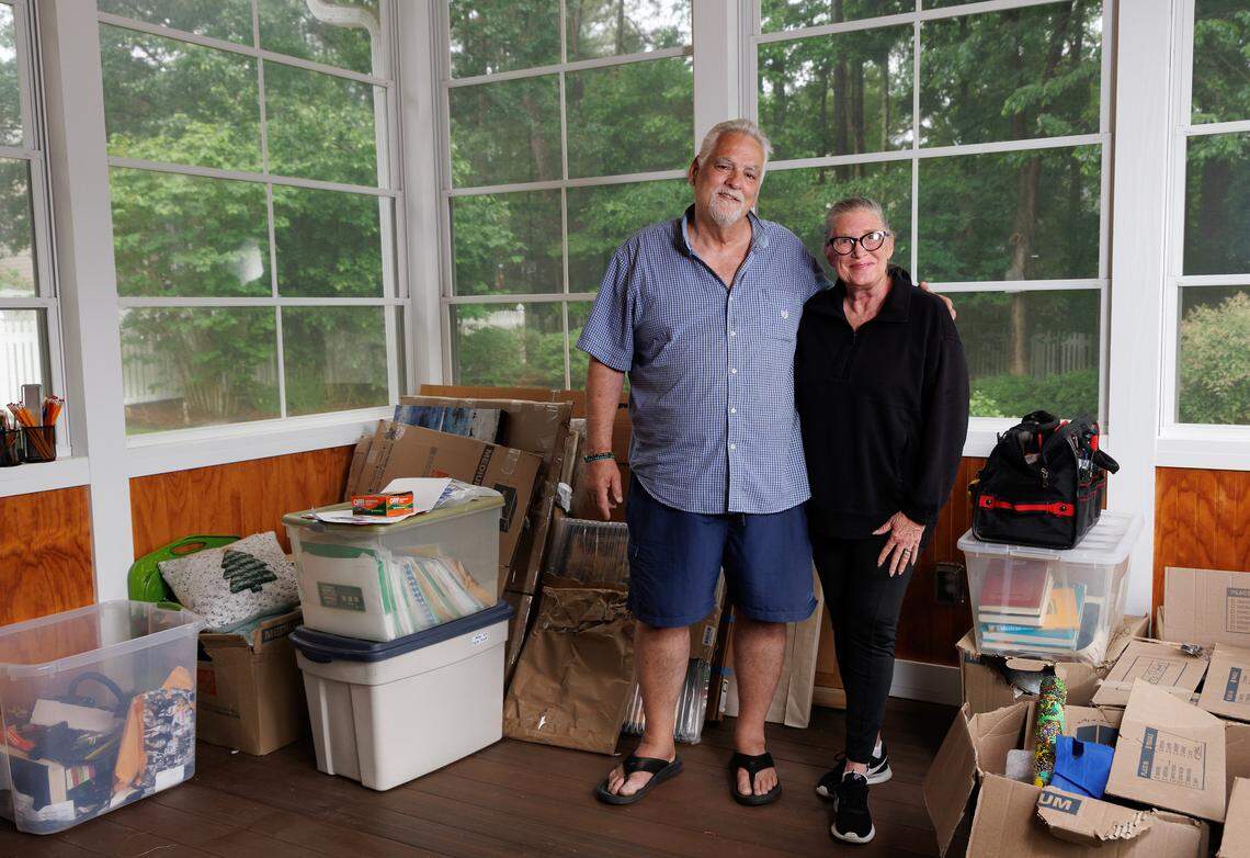 Larry and Annabella Vagonis pose for a portrait among storage bins and moving boxes at their new home in Chapel Hill, N.C. on Sunday, May 4, 2025. The couple recently relocated to the Triangle from northern Virginia, where they had lived for decades.