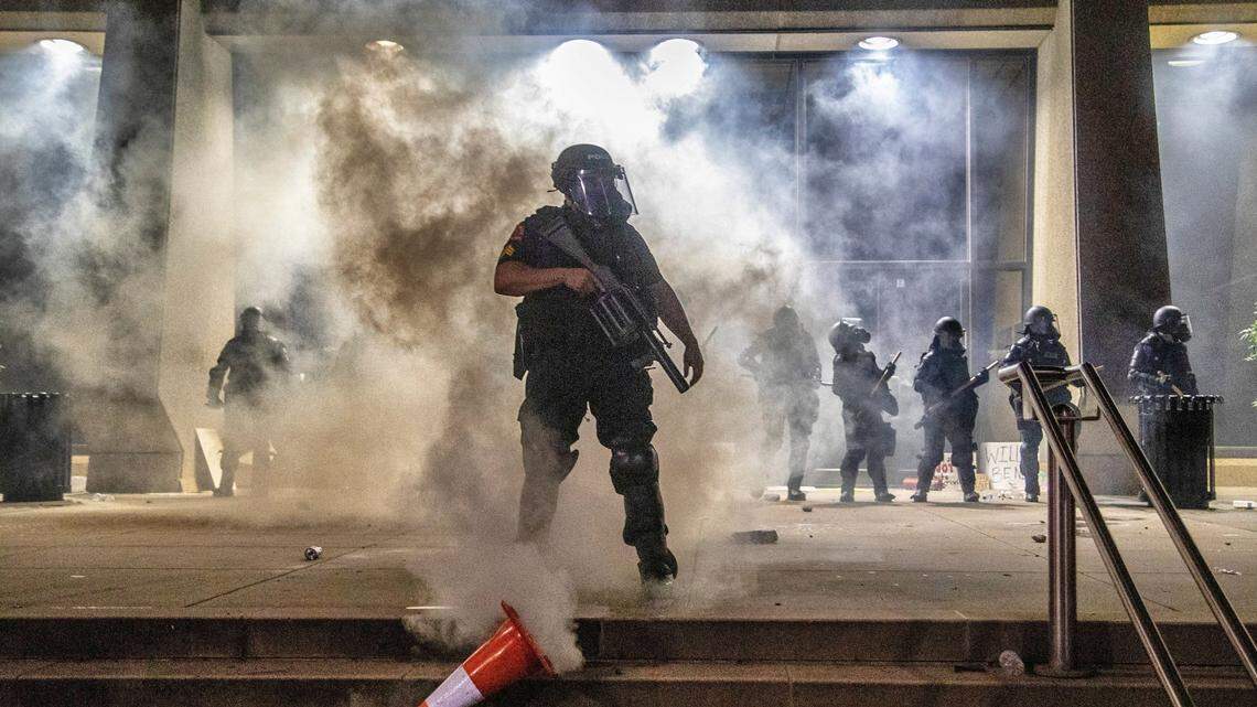 A police officer kicks over a safety cone that protesters placed over a tear gas canister as police in riot gear protect the courthouse during a protest in downtown Raleigh Saturday, May 30, 2020.