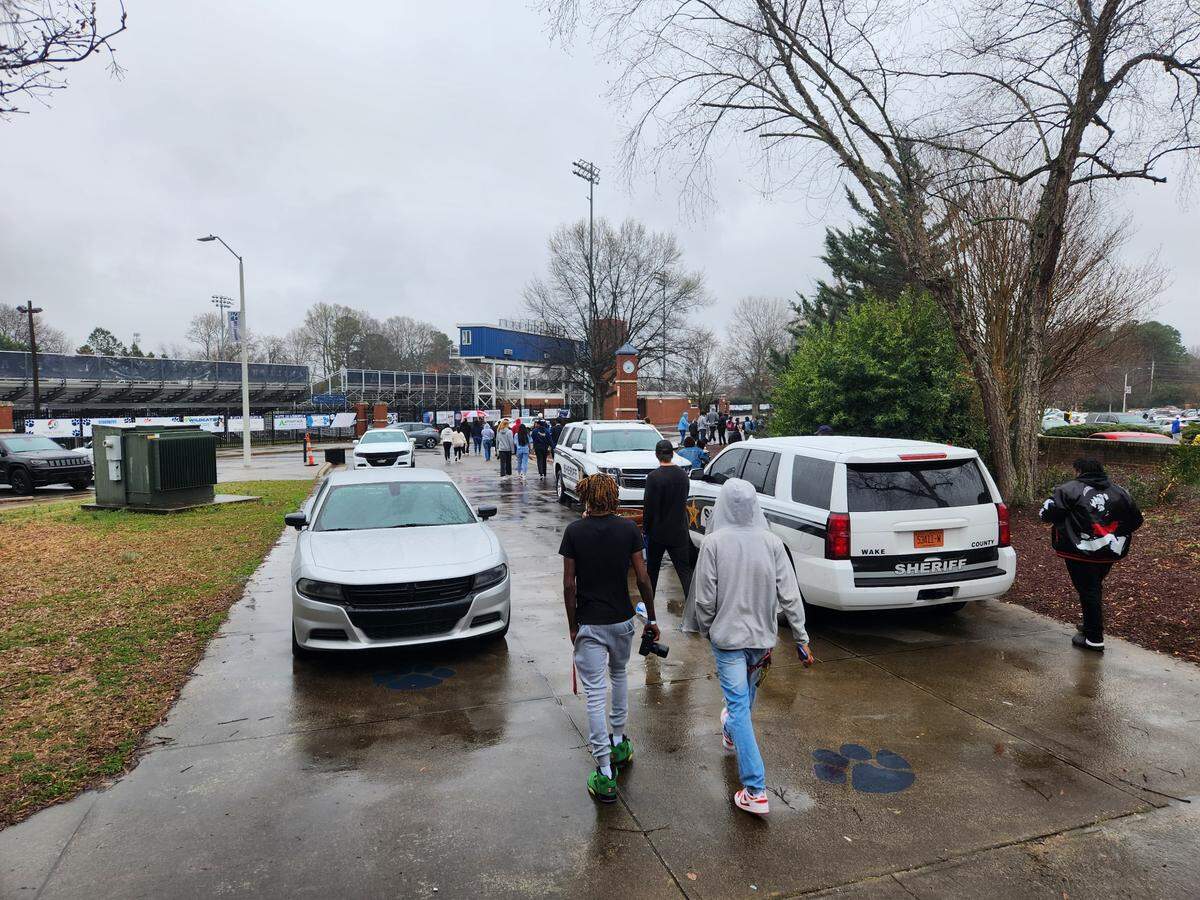 Students and others walk past Wake County Sheriff’s Office cars after the Millbrook High and Jordan High basketball game Saturday Feb. 25, 2023. Millbrook hosted the game.