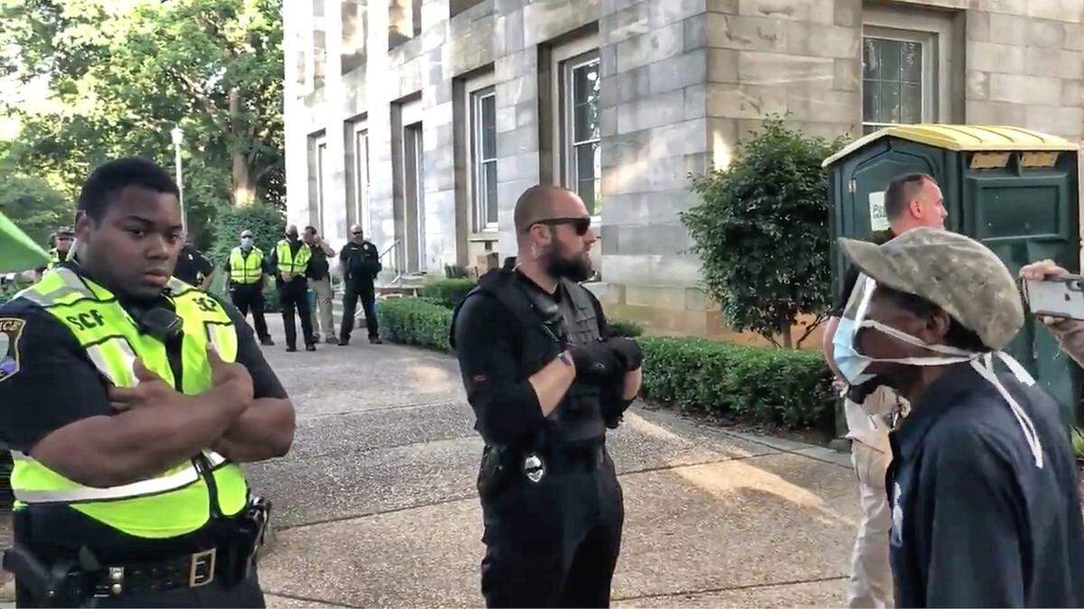 A protester (right) tries to engage a State Capitol Police officer (far left) during a rally Saturday night on the grounds of the state capitol in downtown Raleigh, N.C. June 6, 2020.