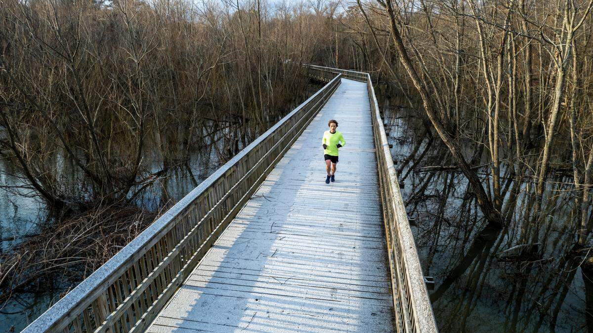 Zachary Bugg runs along Crabtree Creek Trail in Raleigh after a light dusting of snow accumulated on the boardwalk structures on the trail Saturday morning, Jan. 29, 2022.