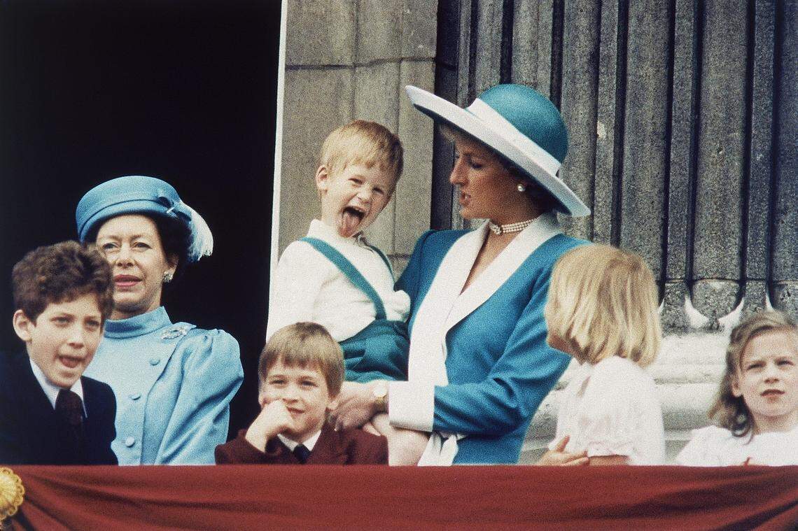 Britain's Prince Harry, held by his mother, Princess Diana, sticks out his tongue for the cameras on the balcony of Buckingham Palace in London on June 11, 1988.