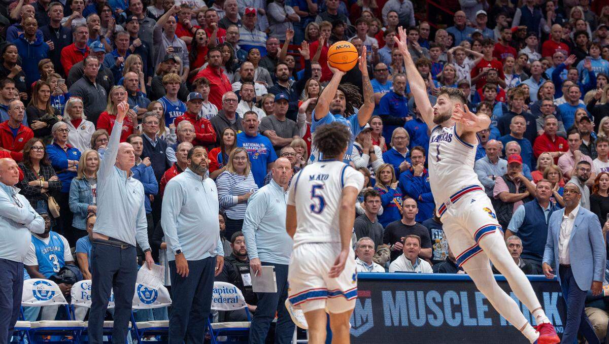 All eyes are on North Carolina guard Elliot Cadeau (3) as he launches a three-point basket at the buzzer under pressure from Kansas center Hunter Dickinson (1) on Friday, November 8, 2024 at Allen Fieldhouse in Lawrence, Kansas. Cadeau missed the shot to secure Kansas’ 92-89 victory.