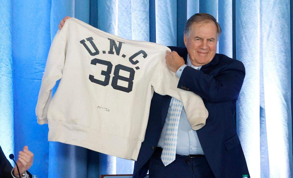 New North Carolina head football coach Bill Belichick holds up his father’s Carolina sweatshirt during a press conference announcing his hiring at UNC Chapel Hill in December 2024.