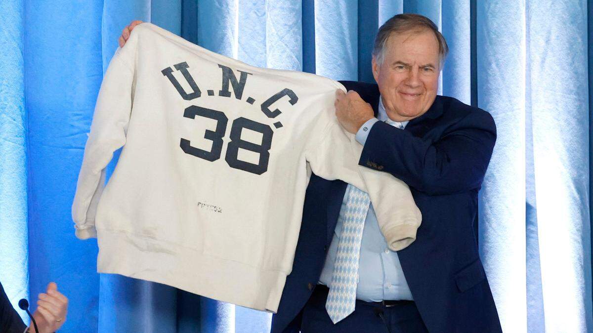 New North Carolina head football coach Bill Belichick holds up his father’s Carolina sweatshirt during a press conference announcing his hiring at the Loudermilk Center for Excellence at UNC in Chapel Hill, N.C., Thursday, Dec. 12, 2024.