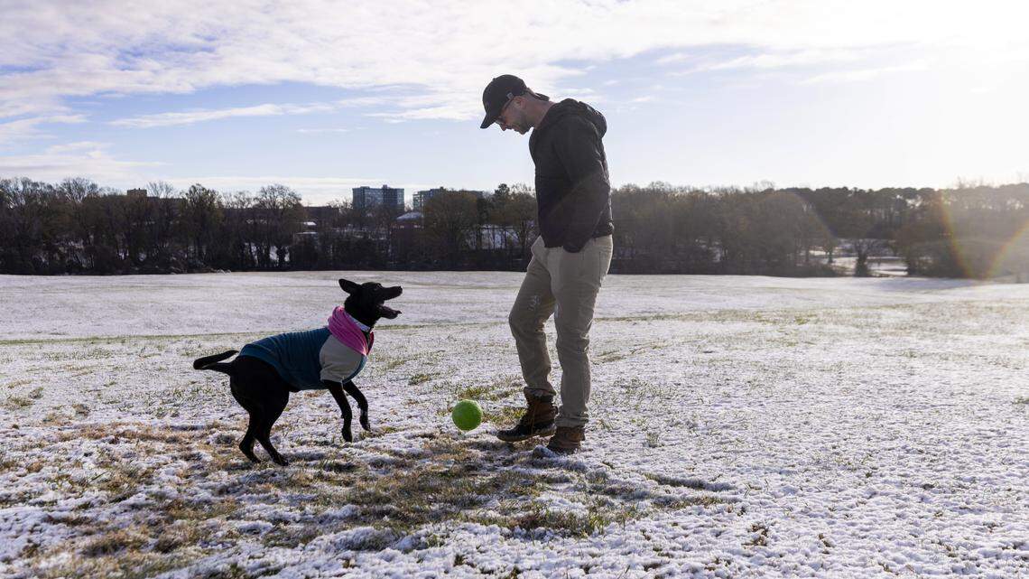 Dustin Shewman of Raleigh plays fetch with his dog, Maebelline, in the Big Field at Dorothea Dix Park after a dusting of snow that accumulated overnight on Tuesday morning, Dec. 9, 2025.