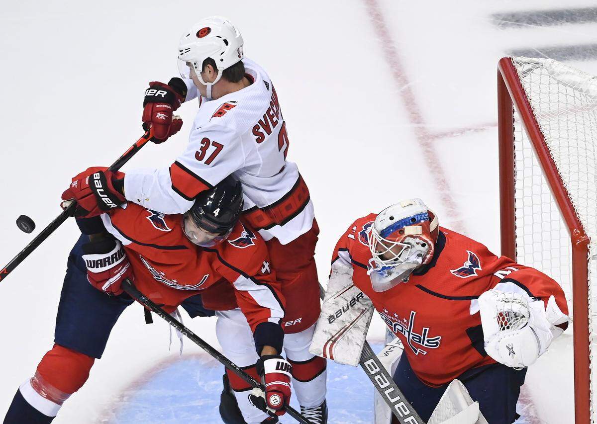 Carolina Hurricanes right wing Andrei Svechnikov (37) battles for the loose puck against Washington Capitals defenseman Brenden Dillon (4) as Capitals goaltender Braden Holtby (70) looks on during the third period of an exhibition NHL hockey game Wednesday, July 29, 2020 in Toronto. (Nathan Denette/The Canadian Press via AP)