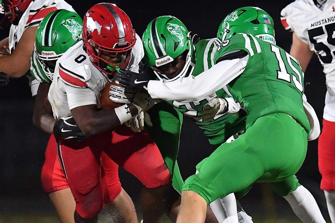 Middle Creek running back Jayden Spencer (0)  rushes for the first down against Cary's Michael McDonald (15) and James Melvin (22) during the first half. The Cary Imps and the Middle Creek Mustangs met in a conference football game in Cary, N.C. on October 24, 2025