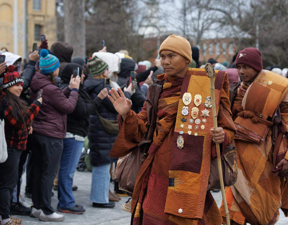 A Buddhist monk waves to supporters in Dorothea Dix Park on Saturday.