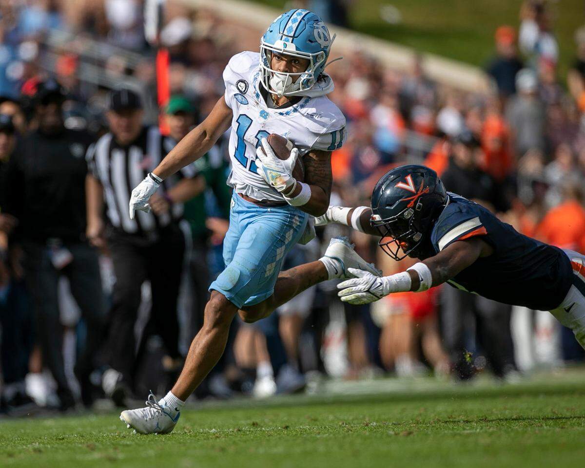 North Carolina’s Josh Downs (11) looks for running room against Virginia’s Coen King (9) after a 32-yard pass reception from quarterback Drake Maye in the third quarter on Saturday, November 5, 2022 at Scott Stadium in Charlottesville, Va.