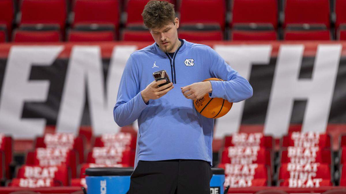 North Carolina center Henri Veesaar (13) checks his phone as his teammates warm up for their game against N.C. State on Tuesday, February 17, 2026 at Lenovo Center in Raleigh, N.C.
