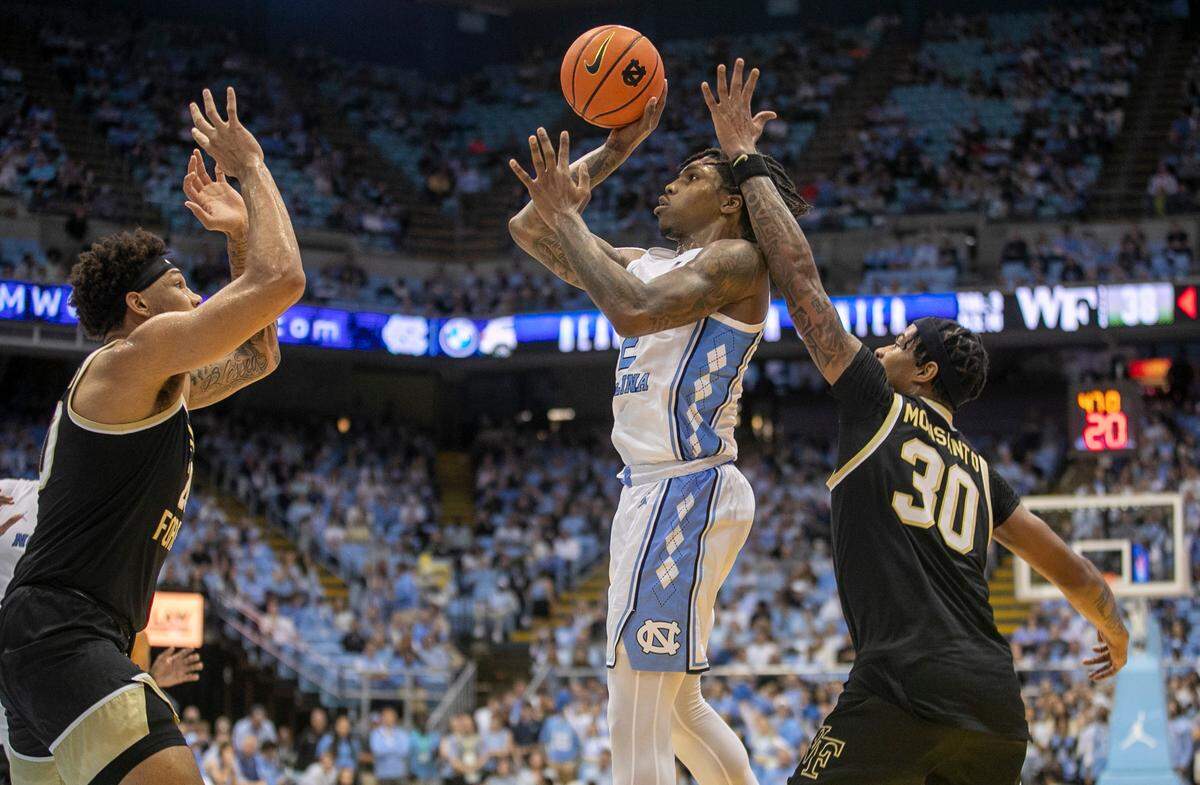 North Carolina’s Caleb Love (2) puts up a shot against Wake Forest’s Davion Bradford (20) and Damari Monsanto (30) in the first half on Wednesday, January 4, 2023 at the Smith Center in Chapel Hill, N.C.