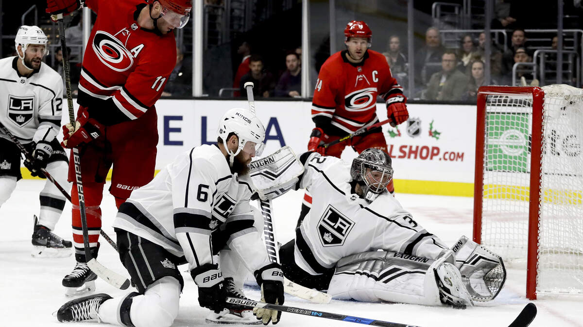 Los Angeles Kings goaltender Jonathan Quick blocks shot by Carolina Hurricanes center Jordan Staal as defenseman Jake Muzzin looks on during the third period of an NHL hockey game in Los Angeles, Sunday, Dec. 2, 2018.