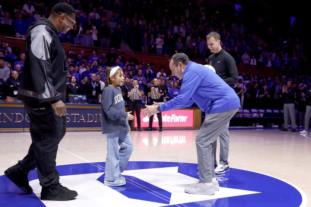 Former Duke basketball coach Mike Krzyzewski greets Howard coach Kenneth Blakeney’s daughter Naomi, 8, as he, Duke coach Jon Scheyer and Blakeney greet each other before Duke’s game against Howard at Cameron Indoor Stadium in Durham, N.C., Sunday, Nov. 23, 2025. Scheyer and Blakeney played under Coach K.