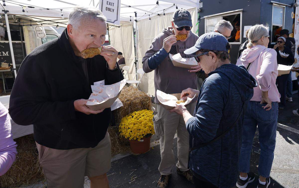 Attendees including Jim Kisthardt, left, taste fried brown sugar corn from Oak City Fish and Chips during the News and Observer’s Foodie's Tour of the State Fair at the N.C. State Fair in Raleigh, N.C., Friday, October 17, 2025.