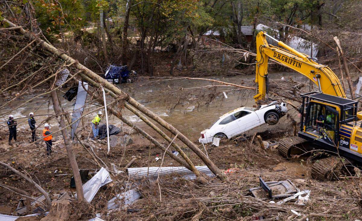 An excavator moves a car to a safer position so a FEMA search and rescue team from Maryland can search it for possible human remains in Swannanoa on Sunday, Oct. 6, 2024 after Tropical Storm Helene flooded the Swannanoa River. North Carolina officials have confirmed 76 deaths from Tropical Storm Helene.