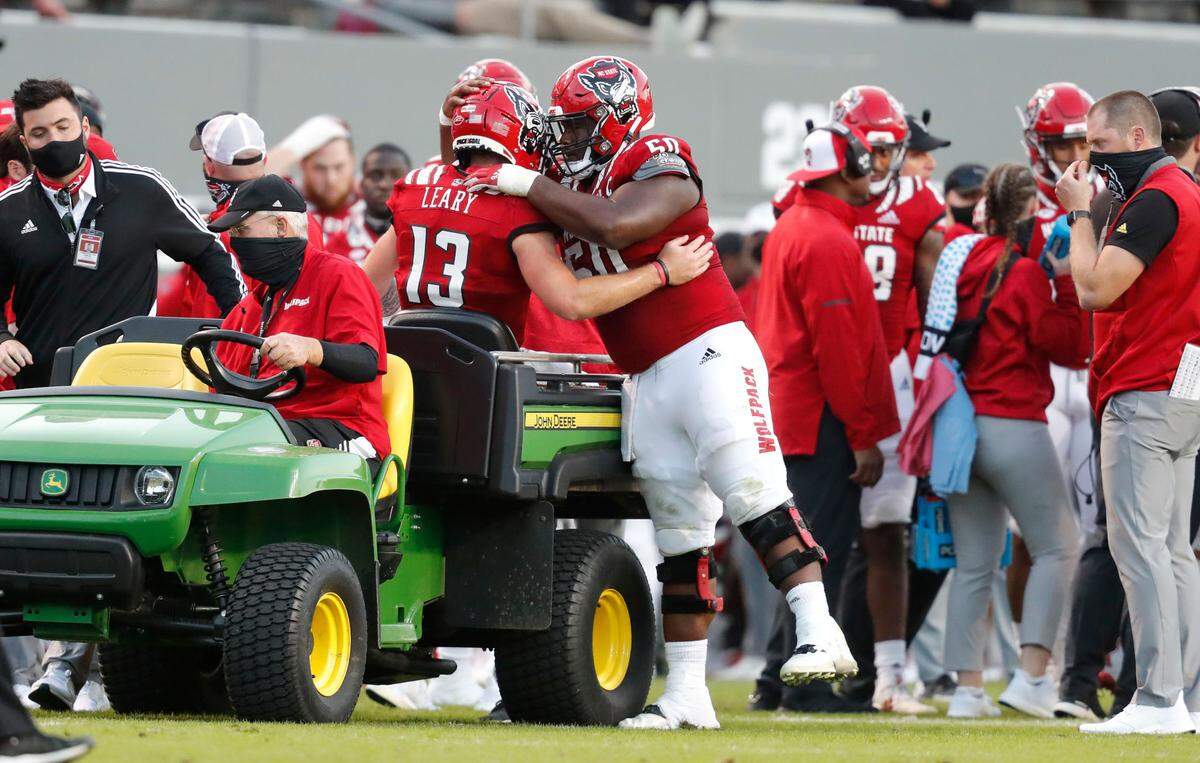 N.C. State’s Grant Gibson (50) hugs quarterback Devin Leary (13) as he is taken off the field after being injured during the second half of N.C. State’s 31-20 victory over Duke at Carter-Finley Stadium in Raleigh, N.C., Saturday, Oct. 17, 2020.
