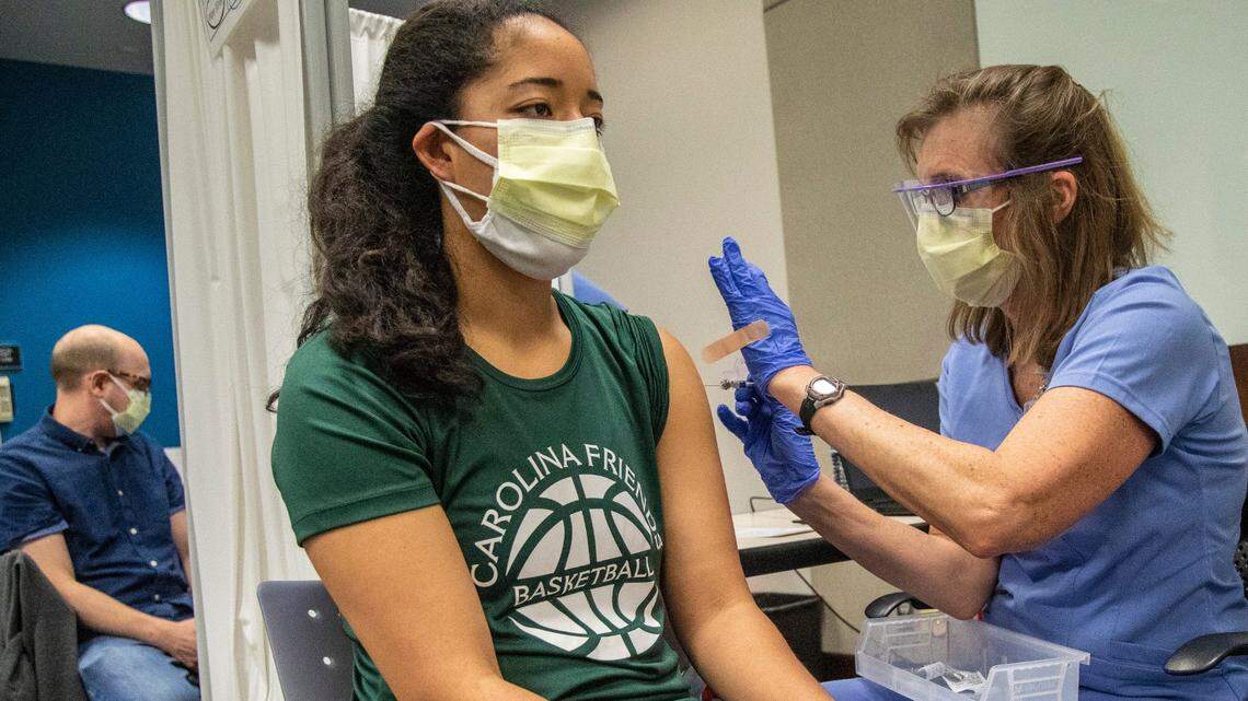 Alvina Long, right, administers a dose of Pfizer coronavirus vaccine to Allegra Berry, a preschool teacher and private school athletics coach, while high school English teacher Keith Gerdes, background, receives a vaccine as well Thursday, Feb. 25, 2021 at the Friday Center in Chapel Hill.