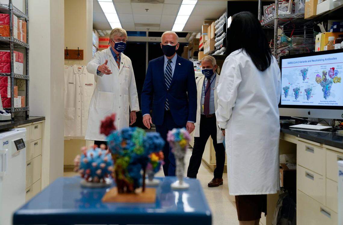 National Institutes of Health Director Francis Collins, left, and Dr. Anthony Fauci, director of the National Institute of Allergy and Infectious Diseases, second from right, walk with President Joe Biden as he visits the Viral Pathogenesis Laboratory at the National Institutes of Health, Thursday, Feb. 11, 2021, in Bethesda, Md. Kizzmekia Corbett, an immunologist with the Vaccine Research Center at the NIH looks on at right.