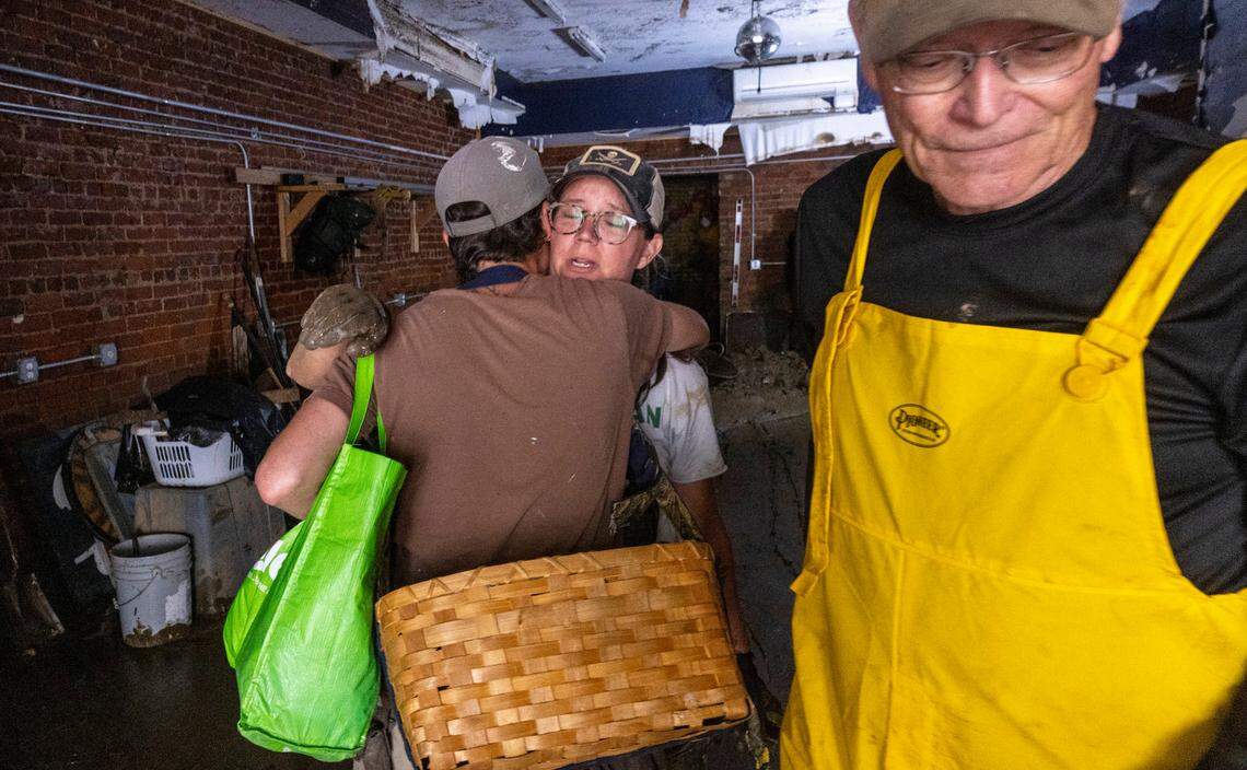 Sarah Pike, center, gets a hug from her friend Jen Dombrowski who arrived to help Pike clean up her business in downtown Marshall on Tuesday, Oct. 1, 2024 after the French Broad River caused catastrophic flooding. The remnants of Hurricane Helene caused widespread flooding, downed trees, and power outages in western North Carolina.