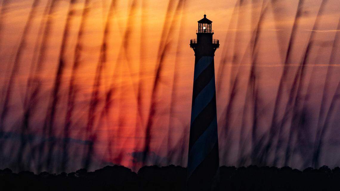 The sun sets behind the Cape Hatteras Light Station in Buxton Thursday, May 19, 2022.