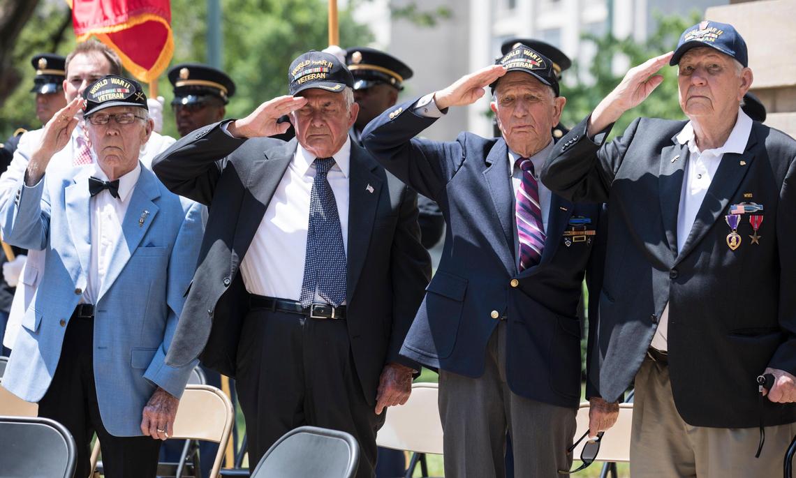 Sergeant Hubert Edwards of Sanford, left, and fellow World War II veterans salute as a band plays the national anthem outside of the North Carolina State Capitol during a ceremony commemorating the 75th anniversary of D-Day on June 6, 2019.