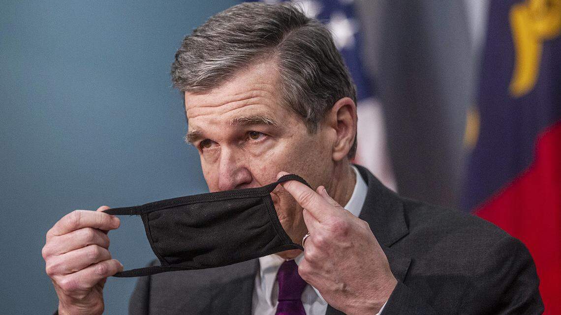 Gov. Roy Cooper removes his mask before speaking during a briefing on North Carolina’s coronavirus pandemic response Tuesday, Dec.22, 2020 at the NC Emergency Operations Center in Raleigh.