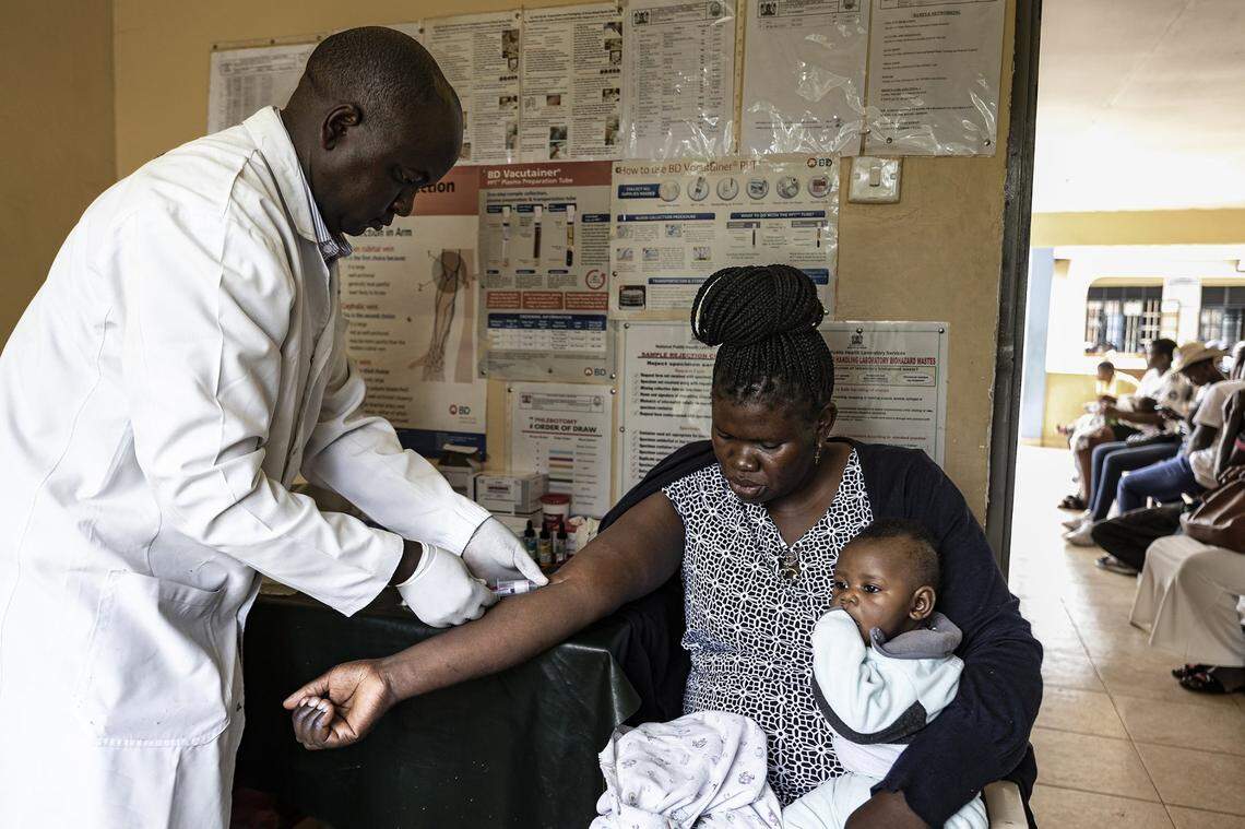 Martin Agunda (left), a lab technician at Kuoyo Sub-county Hospital, once supported by USAID, in Kisumu, prepares to test a viral load sample from Ruth Gweyi (right), a mother living with HIV on April 24, 2025, in Kisumu, Kenya. Kisumu has one of the highest HIV rates in Kenya, with around 17.6% of the adult population are living with the virus, nearly five times the national average of 4.5%. In 2025, Kisumu has become a focal point of a growing healthcare crisis, as funding cuts from the United States Agency for International Development (USAID) ripple through the local health system.
