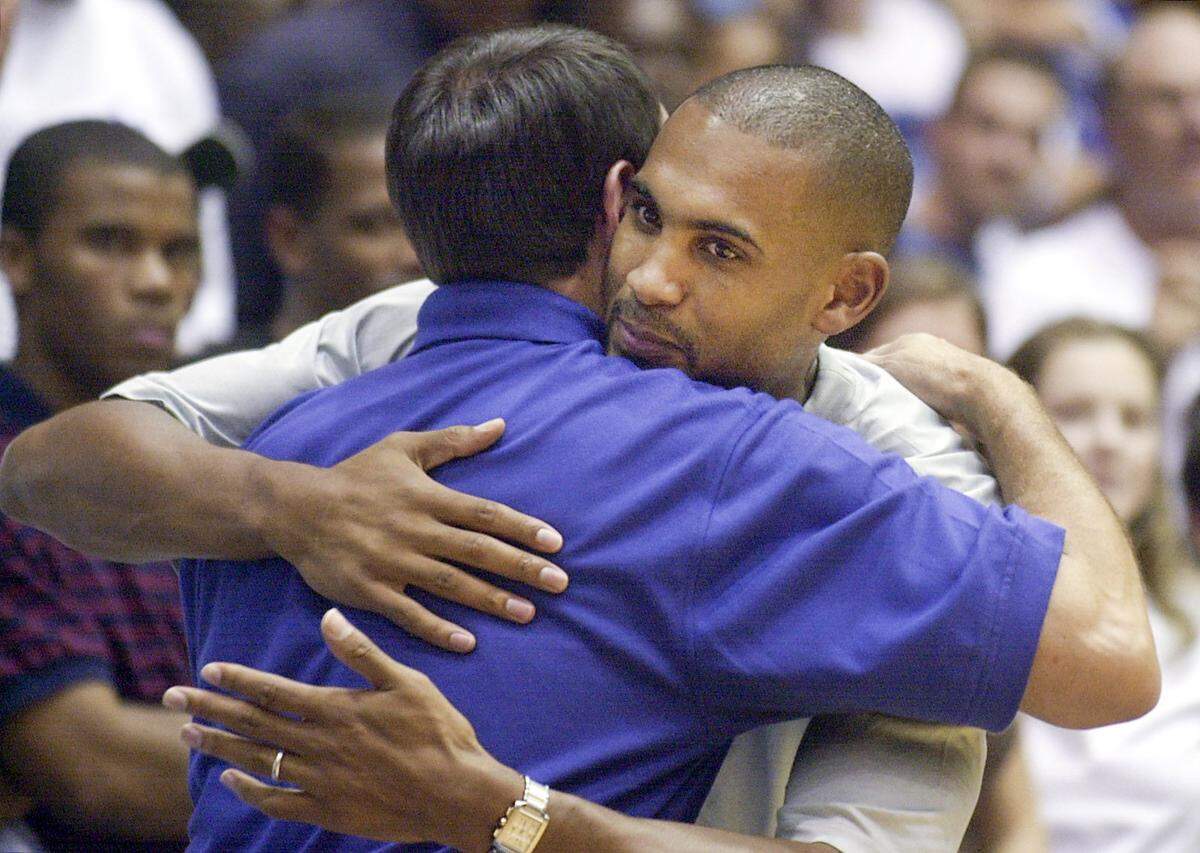 Duke basketball head coach Mike Krzyzewski gets a hug from former player Grant Hill (at right) in Cameron Indoor Stadium prior to a fund raising event held Saturday for the Birch Street Recreation Center.