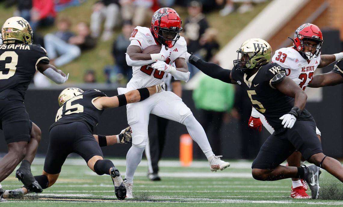 N.C. State running back Kendrick Raphael (20) looks to escape from Wake Forest’s Nick Andersen (45) and Kendron Wayman (5) during the first half of N.C. State’s game against Wake Forest at Allegacy Stadium in Winston-Salem, N.C., Saturday, Nov. 11, 2023.