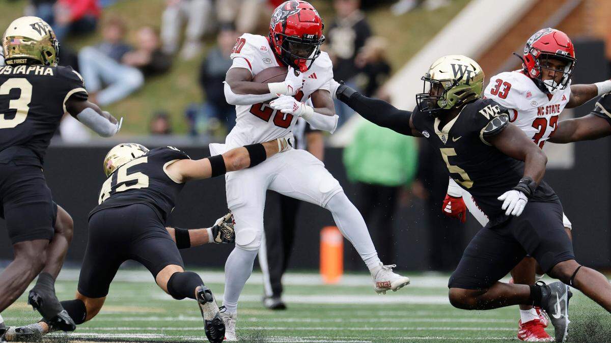 N.C. State running back Kendrick Raphael (20) looks to escape from Wake Forest’s Nick Andersen (45) and Kendron Wayman (5) during the first half of N.C. State’s game against Wake Forest at Allegacy Stadium in Winston-Salem, N.C., Saturday, Nov. 11, 2023.