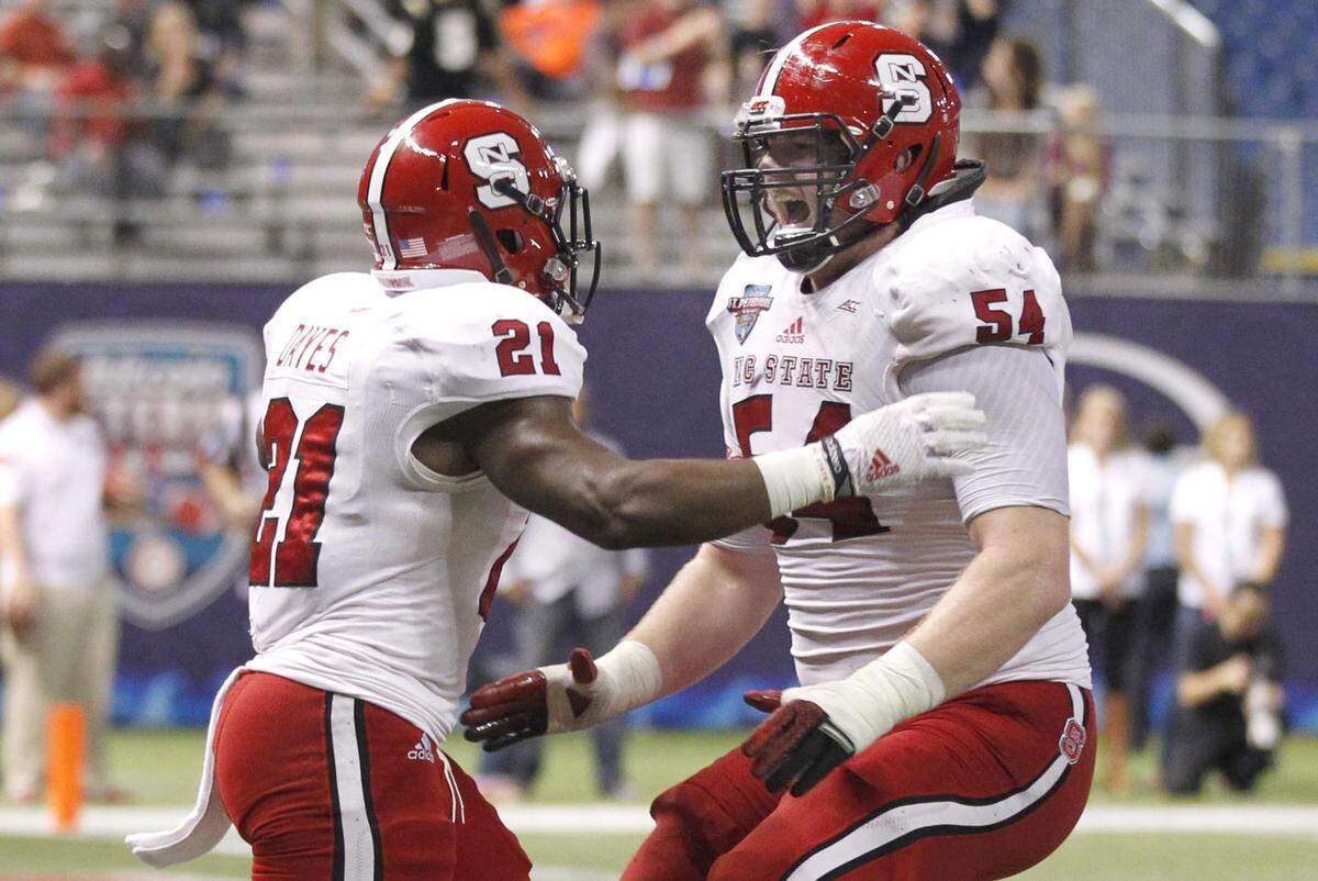 N.C. State’s Joe Thuney (54) celebrates with Matt Dayes (21) after Dayes ran for a 15-yard touchdown during the Wolfpack’s game against UCF in the Bitcoin St. Petersburg Bowl at Tropicana Field in St. Petersburg, Fla. in Dec. 2014.
