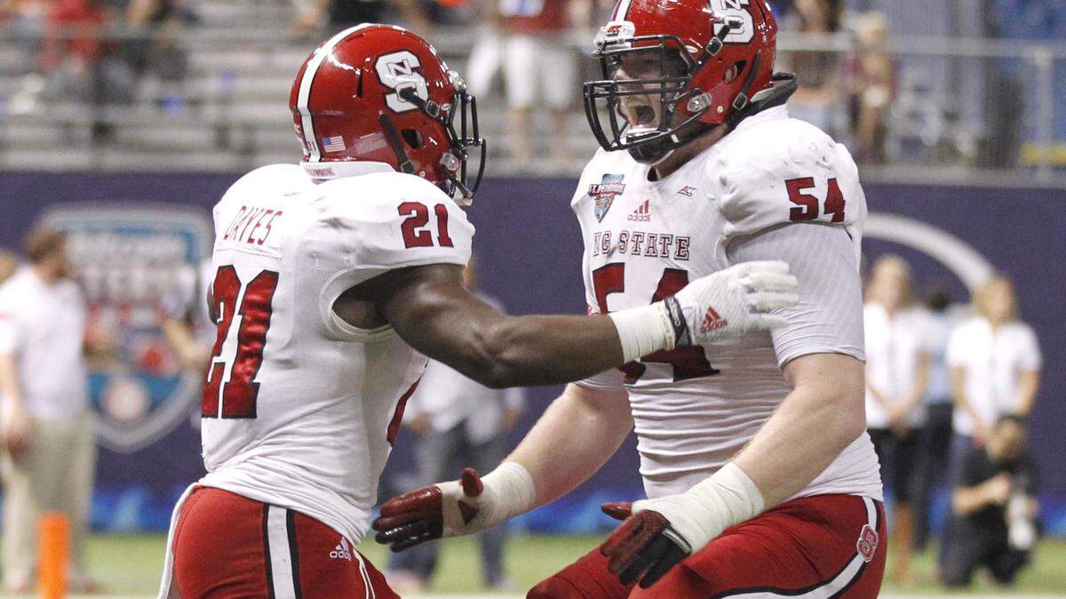 N.C. State’s Joe Thuney (54) celebrates with Matt Dayes (21) after Dayes ran for a 15-yard touchdown during the Wolfpack’s game against UCF in the Bitcoin St. Petersburg Bowl at Tropicana Field in St. Petersburg, Fla. in Dec. 2014.