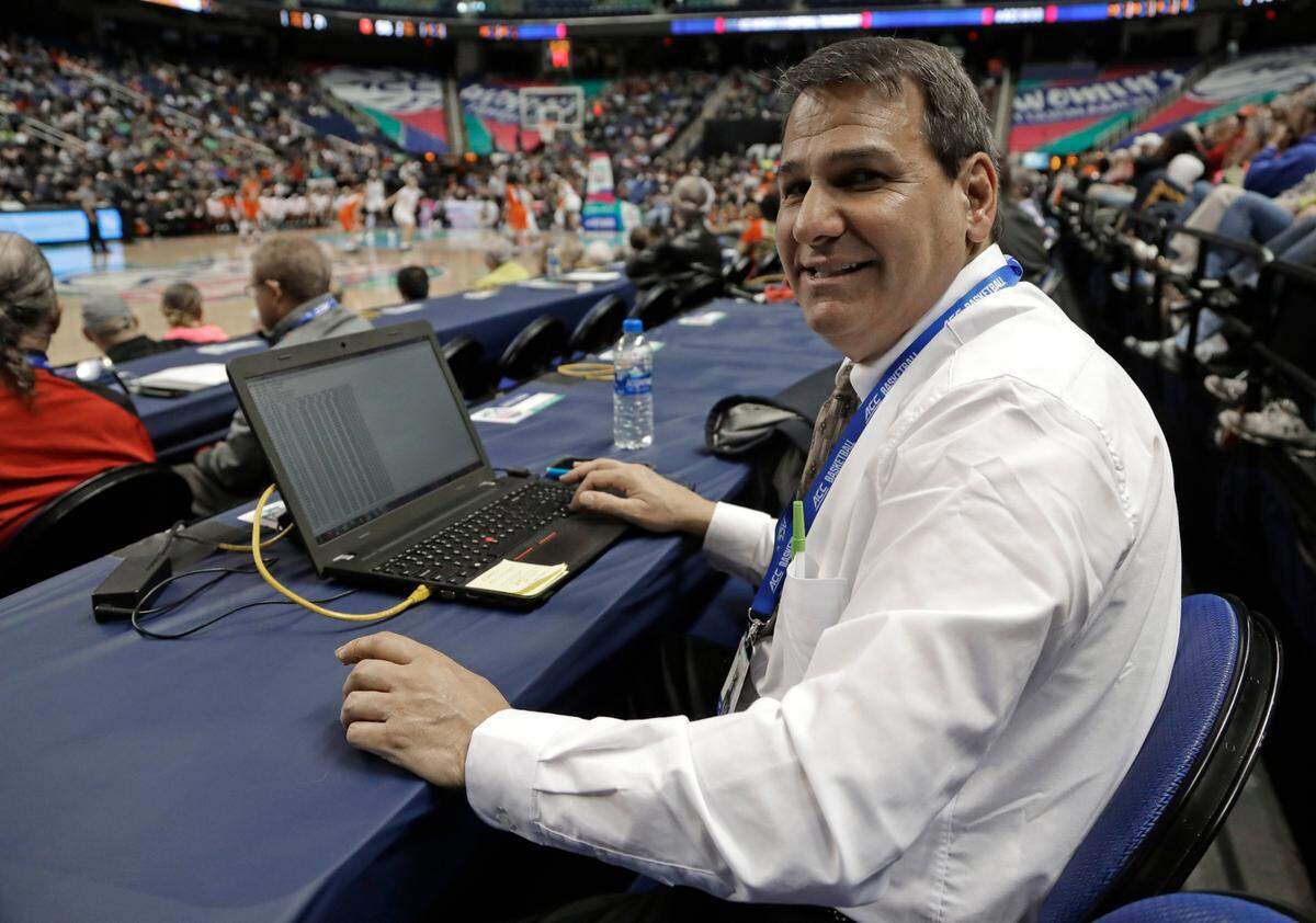 In this photo taken March 9, 2019 Precision Time inventor Mike Costabile, a former referee, poses for a photo as he keeps track of a log of the system during the second half of an Atlantic Coast Conference women’s tournament basketball game in Greensboro, N.C. The Precision Time system created more than two decades ago by Costabile currently is used at nearly every level of the sport, including the NBA and college basketball’s NCAA Tournament. Costabile estimates the ability to stop the clock automatically on a referee’s whistle can save roughly 90 seconds formerly lost to reaction time when timekeepers manually stopped the clock. (AP Photo/Chuck Burton)