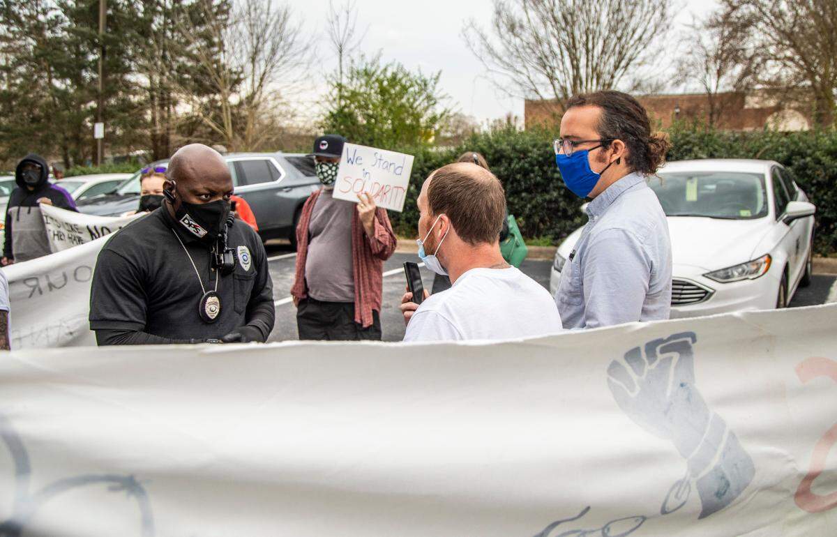 Probation officers try to disperse a protest Wednesday, March 24, 2021 outside a Quality Inn in Durham. The demonstrators were protesting living conditions and other concerns related to people being kept at the hotel after they are released from prison. State officials said the hotel was leased for men who are being released from a prison in which they could have been exposed to COVID-19 and who donÕt have another suitable housing plan.
