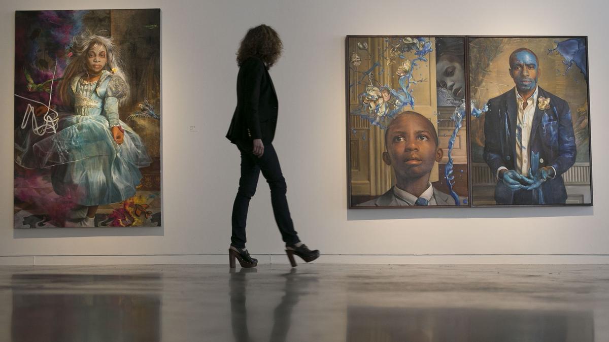 CAM executive director Gab Smith walks through the exhibition “Painting the Roses Red” by painter Margaret Bowland on Wednesday, April 18, 2018, at CAM Raleigh. "Dust Up" (left) and "Tangled Up in Blue" (right, featuring curator Dexter Wimberly and his son as subjects) are part of a series of large-scale paintings by Bowland on exhibit through June 17, 2018.