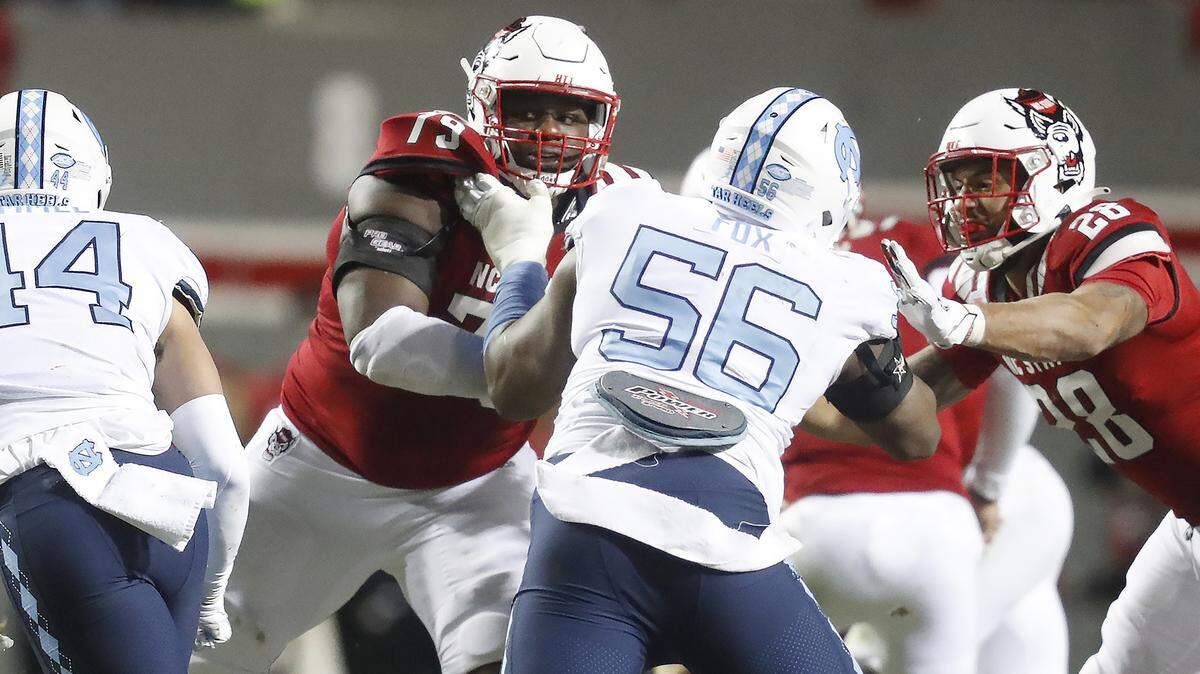 N.C. State offensive tackle Ikem Ekwonu (79) and tight end Dylan Parham (28) block North Carolina defensive lineman Tomari Fox (56) during N.C. State’s 34-30 victory over UNC at Carter-Finley Stadium in Raleigh, N.C., Friday, November 26, 2021.