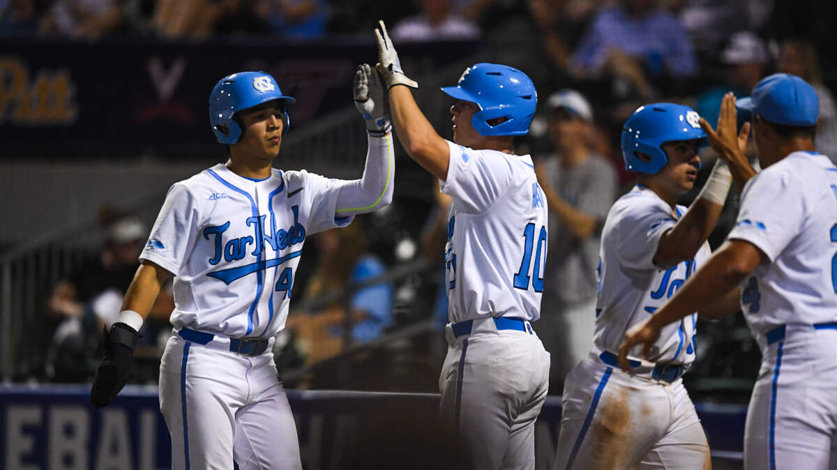 UNC players Tyler Kehoe (10) and Angel Zarate (40) high-five at home plate Tuesday night during their ACC tournament game against Pittsburgh at Truist Field in Charlotte. The Tar Heels lost, 5-3.