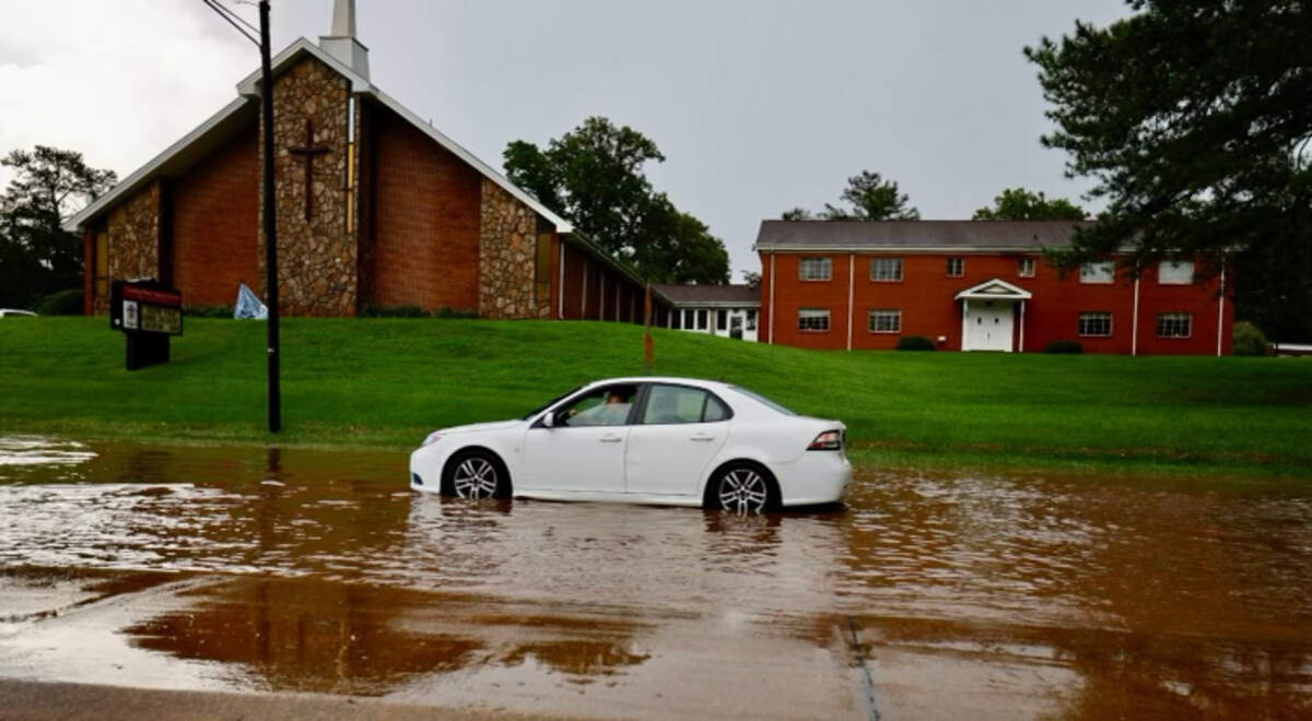 A motorist waits for a push after stalling in water on S. Saunders Street in Raleigh, Sunday evening following heavy rain.