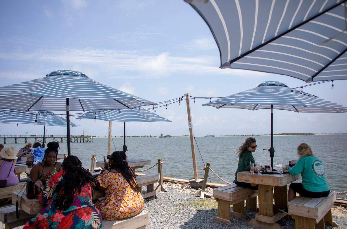 Patrons eat Lunch on a riverside patio at Oliver’s on the Cape Fear in Southport.
