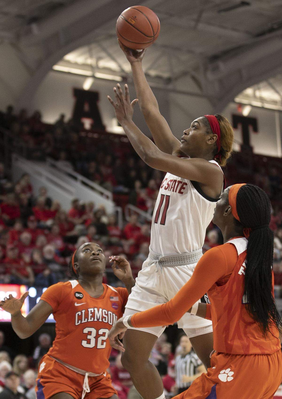 N.C. State’s Kiara Leslie (11) drives to the basket between Clemson’s Chyna Cotton (32) and Kobi Thornton (44) during the second quarter on Thursday, January 24, 2019 at Reynolds Coliseum in Raleigh, N.C. Leslie lead N.C. State with 13 point in their 54-51 victory over Clemson.