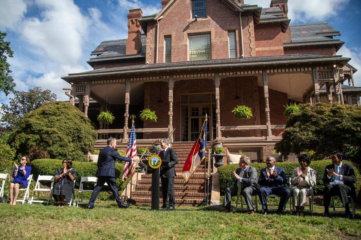 Wolfspeed CEO Gregg Lowe, center left, and Gov. Roy Cooper, shake hands during an economic development announcement ceremony at the Executive Mansion Friday, Sept. 9, 2022. Wolfspeed, a Durham silicon chip manufacturer, will build a new factory in Chatham County promising 1,800 new jobs.