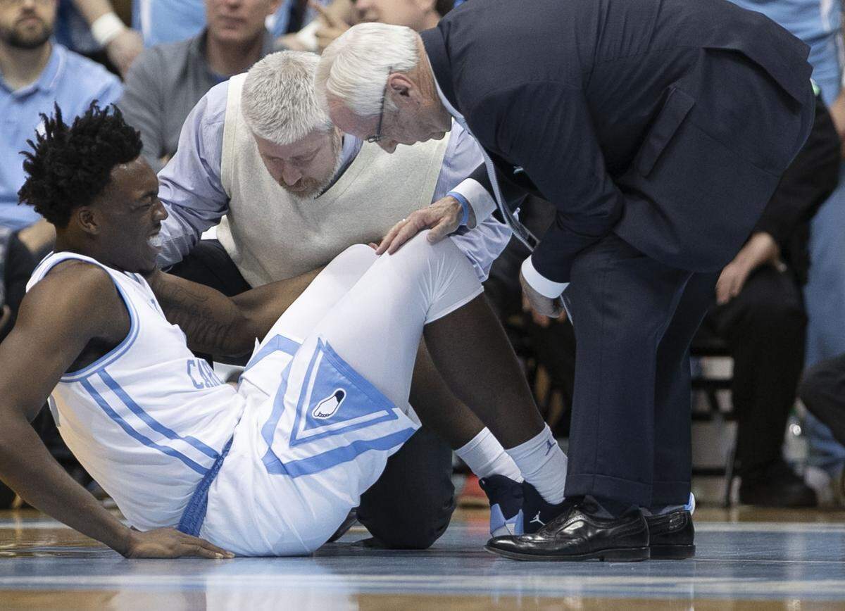 North Carolina coach Roy Williams and trainer Doug Halverson attend to Nassir Little (5) after an injury during the first half against Virginia on Monday, February 11, 2019 at the Smith Center in Chapel Hill, N.C. Little did not return to play.