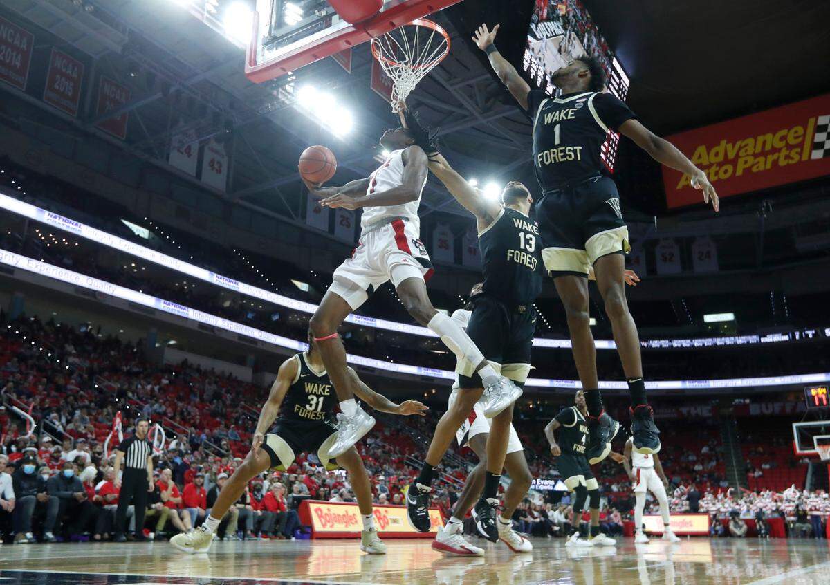 N.C. State’s Dereon Seabron (1) drives past Wake Forest’s Isaiah Mucius (1) and Dallas Walton (13) to shoot during Wake Forest’s 69-51 victory over N.C. State at PNC Arena in Raleigh, N.C., Wednesday, Feb. 9, 2022.