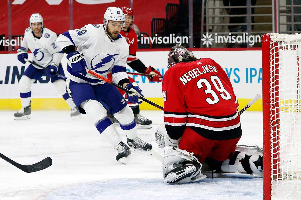 Tampa Bay Lightning’s Barclay Goodrow (19) has the puck swallowed by Carolina Hurricanes goaltender Alex Nedeljkovic (39) during the first period of an NHL hockey game in Raleigh, N.C., Saturday, Feb. 20, 2021. (AP Photo/Karl B DeBlaker)