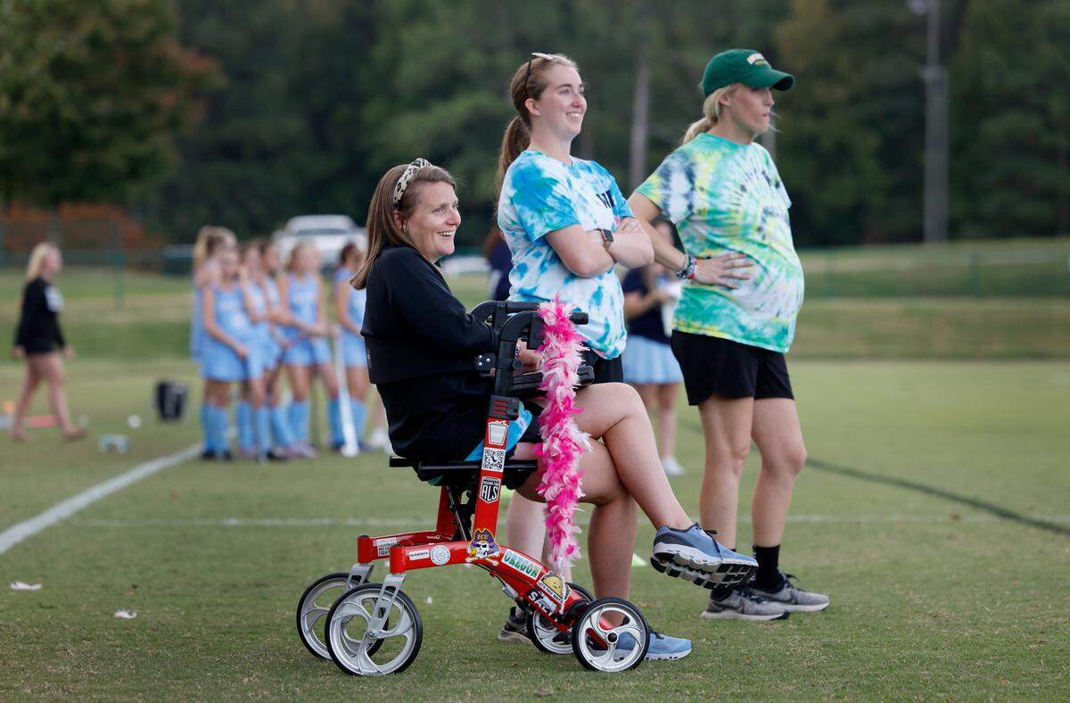 Ravenscroft High School field hockey coaches Whitford Wooten, left, Sydney Rameyan, center, and Meegan Hornan watch the team’s game against St. Mary’s School in Raleigh, N.C., Tuesday, Oct. 10, 2023. Wooten has ALS (amyotrophic lateral sclerosis or Lou Gehrig’s disease), a progressive neurodegenerative disease.
