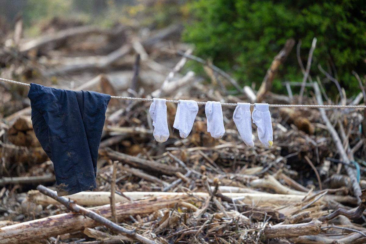Clothes dry in the sunshine against a backdrop of storm debris from Hurricane Helene in the Yancey County village of Pensacola, N.C. on Thursday, October 3, 2024