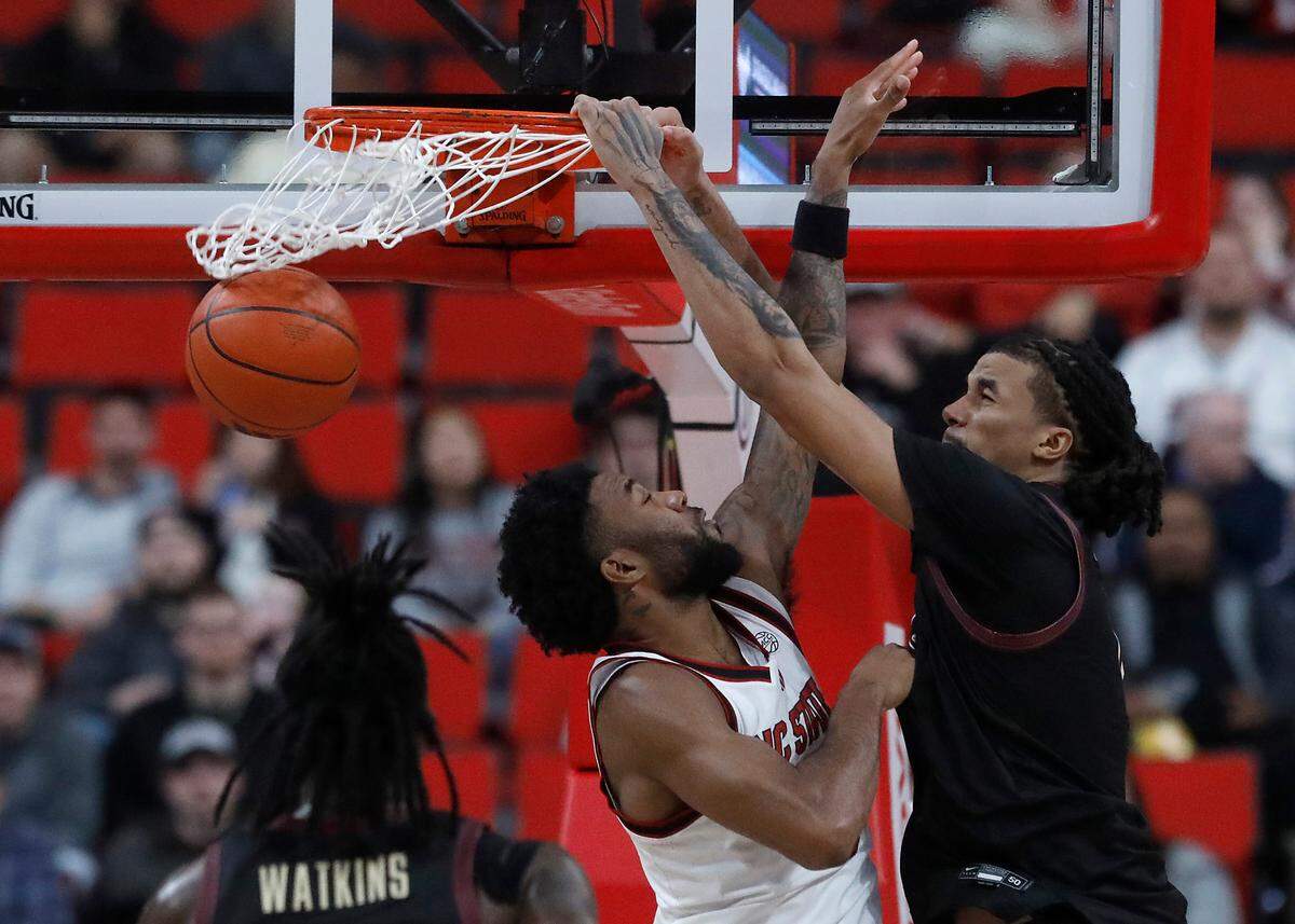 Florida State’s Malique Ewin dunks over N.C. State’s Dontrez Styles during the first half of the Wolfpack’s game on Saturday, Dec. 7, 2024, at Lenovo Center in Raleigh, N.C.